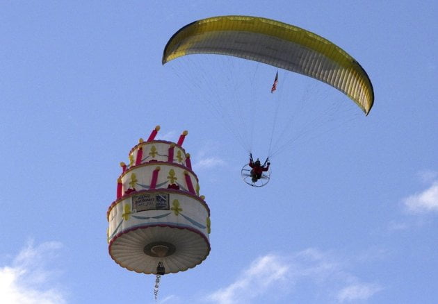 a paraglider flies around a cake shape balloon a paraglider flies around a cake shape balloon